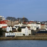 white and brown concrete houses near body of water during daytime