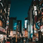 people walking between tall buildings