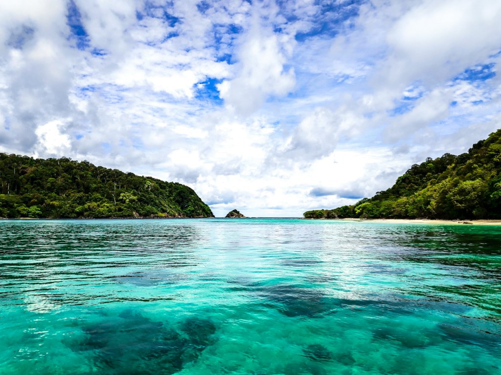 body of water between mountain during daytime