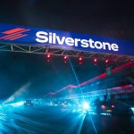 a silver stone sign above a highway at night