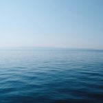 body of water under blue and white sky at daytime
